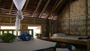 Una habitación con una cama, un banco y un muro tejido.