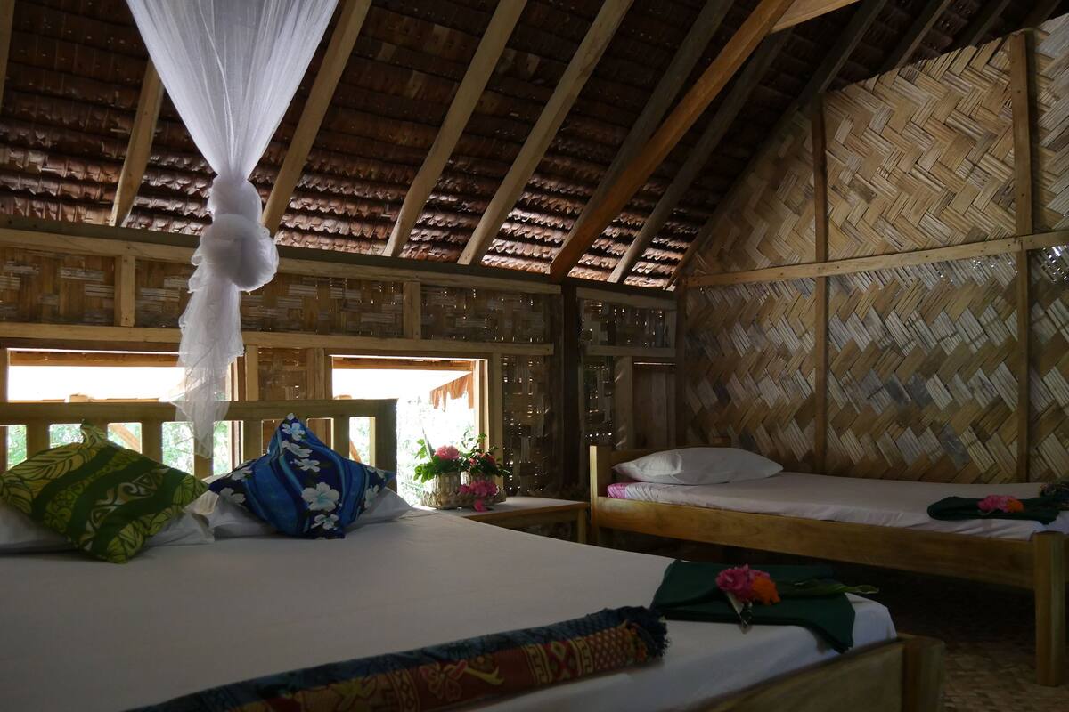 Una habitación con una cama, un banco y un muro tejido.