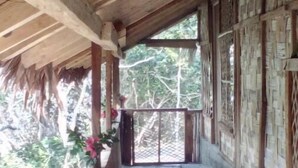 Un corredor al aire libre cubierto, con vigas de madera y suelo de piedra, que conduce a un portón.