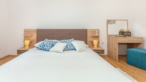 A neatly arranged bedroom with a bed, bedside tables, a desk, and a mirror.