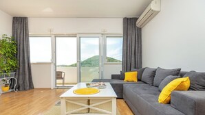 A living room with a grey sofa, yellow cushions, a white coffee table, and a potted plant.