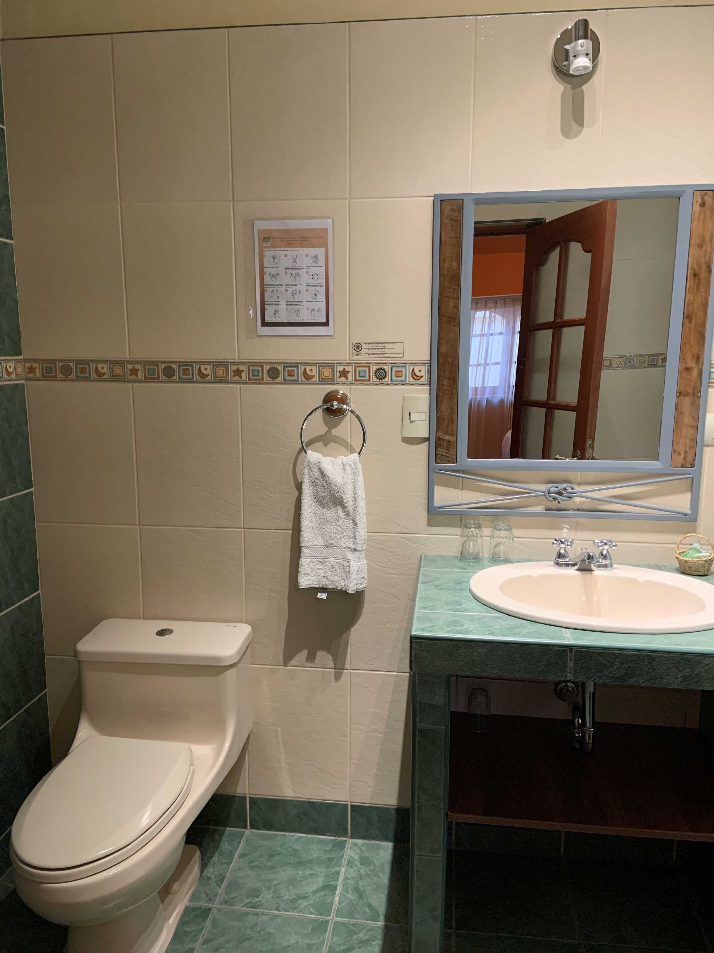 A bathroom with a toilet, sink, and mirror.