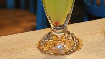 A tall glass with a green beverage, garnished with a slice of lime and a red straw, on a wooden table.