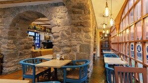 A restaurant interior with stone walls, wooden tables, and blue chairs. - Amerindia Hotel (Cusco)