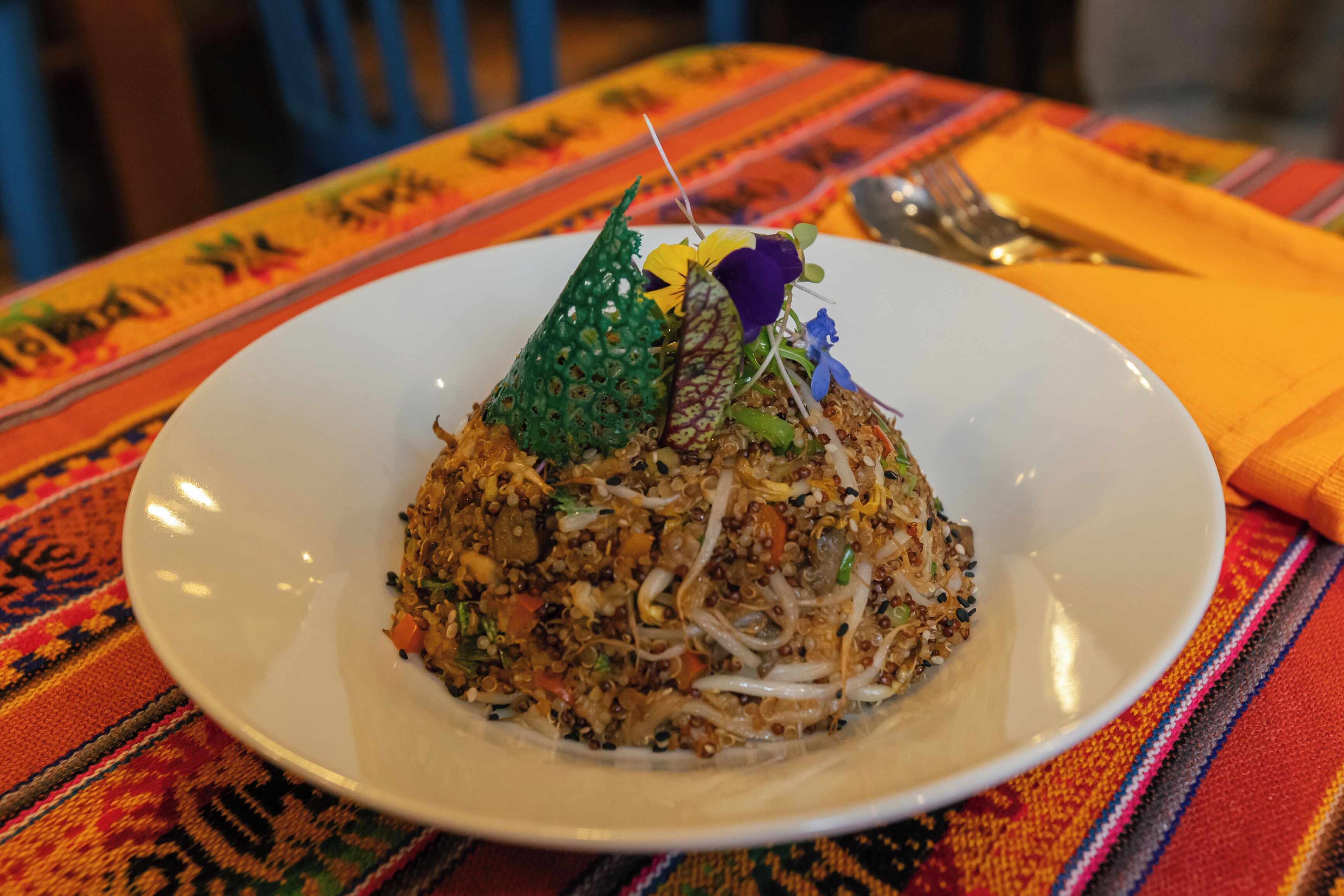 A plate of food with a decorative garnish on a table with a colorful tablecloth.