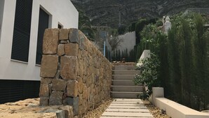 A modern building with a stone wall and a staircase leading to a mountain view. - luxurious, state-of-the-art villa with beautiful views (Denia)