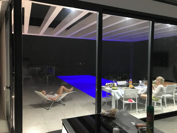 A modern room with a glass wall, a pool, and a dining area. - luxurious, state-of-the-art villa with beautiful views (Denia)