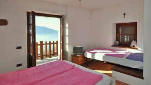 A bedroom with two beds, a television, and a window with a view of mountains.