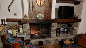 A cozy living room with a stone fireplace, wooden furniture, and a television.