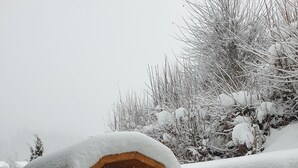 A wooden cabin with a snow-covered roof, a wooden door, and a small porch. - Modern house with unique view and 500m to the Golm ski region (Vorarlberg)
