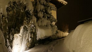 A snow-covered building with icicles hanging from the roof and snow piled against the walls. - Modern house with unique view and 500m to the Golm ski region (Vorarlberg)
