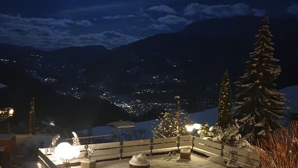 A snow-covered outdoor area with benches and a fence, illuminated by ambient lighting. - Modern house with unique view and 500m to the Golm ski region (Vorarlberg)