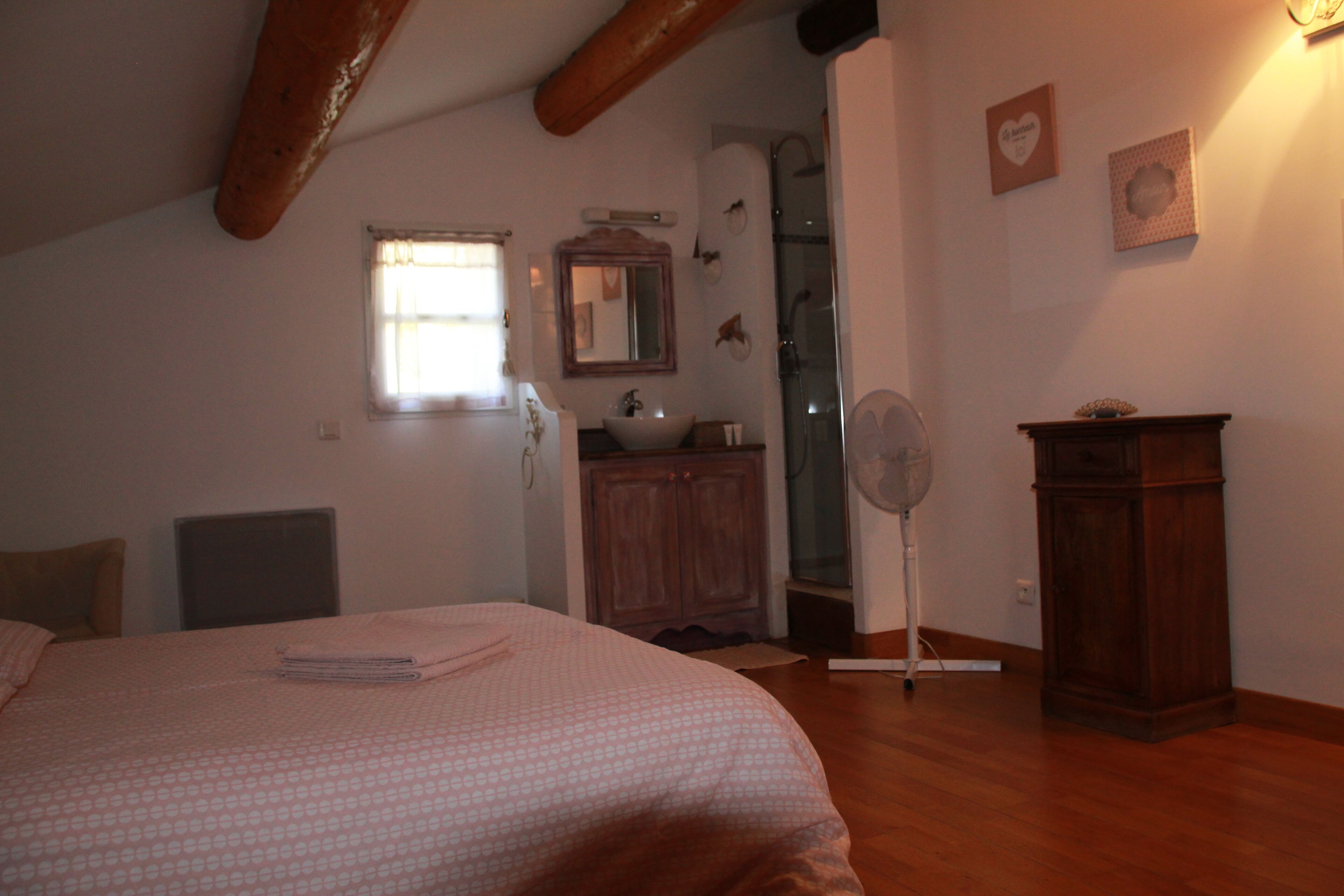 A bedroom with a bed, a wooden cabinet, a mirror, and a window.