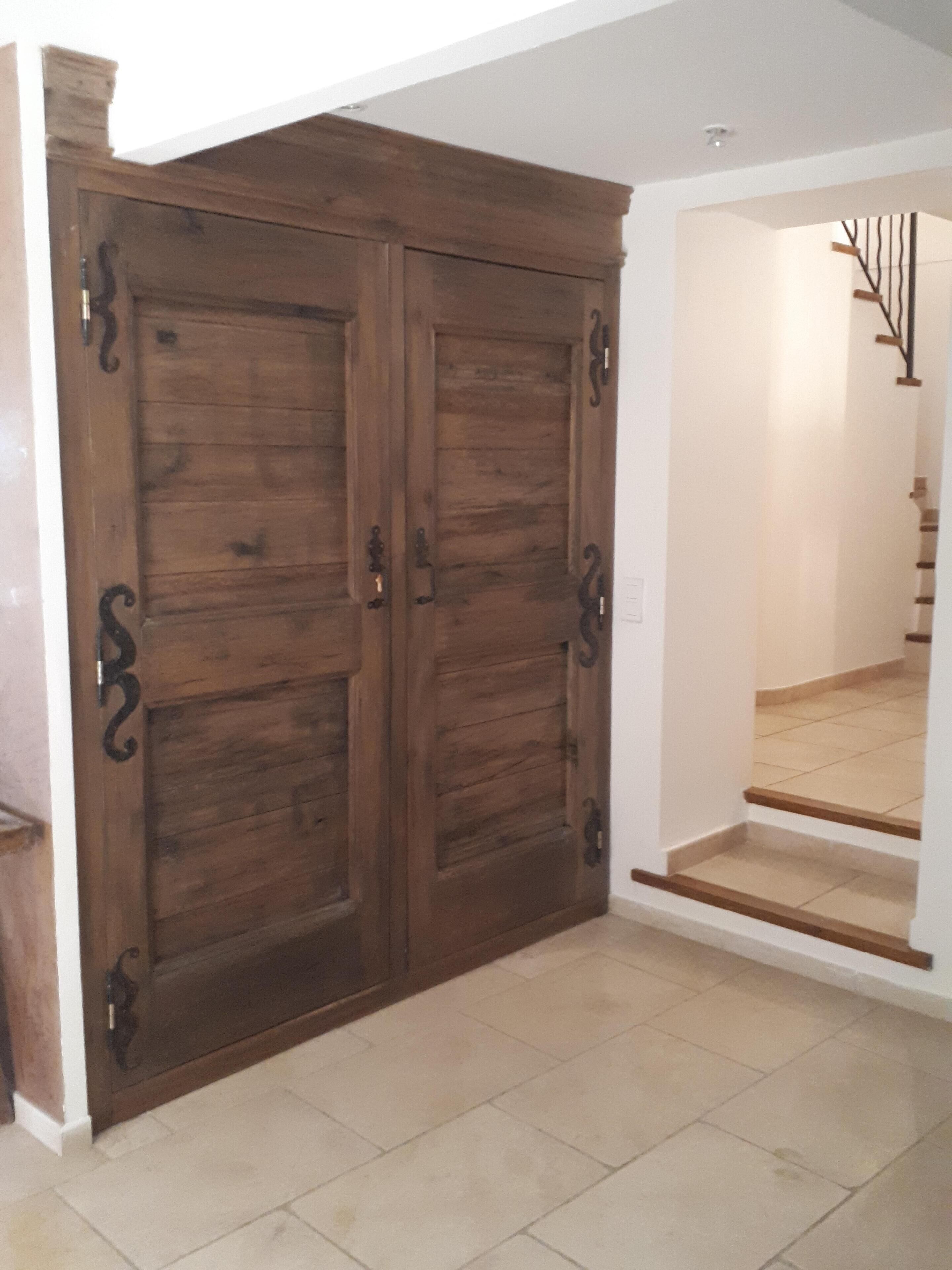 Ein Zimmer mit zwei Holztüren, einer Treppe und einem Fliesenboden.