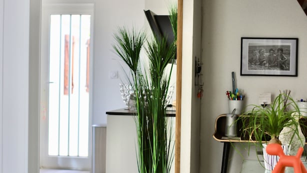 Un salon moderne avec une grande fenêtre, un vase vert et une plante en pot.