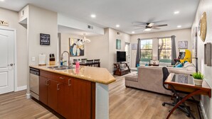 A modern kitchen with granite countertops, wooden cabinets, and a built-in dishwasher. - Quiet 1st Floor, Gated, Pool, Wi-Fi, Free Parking, Gym (Phoenix)