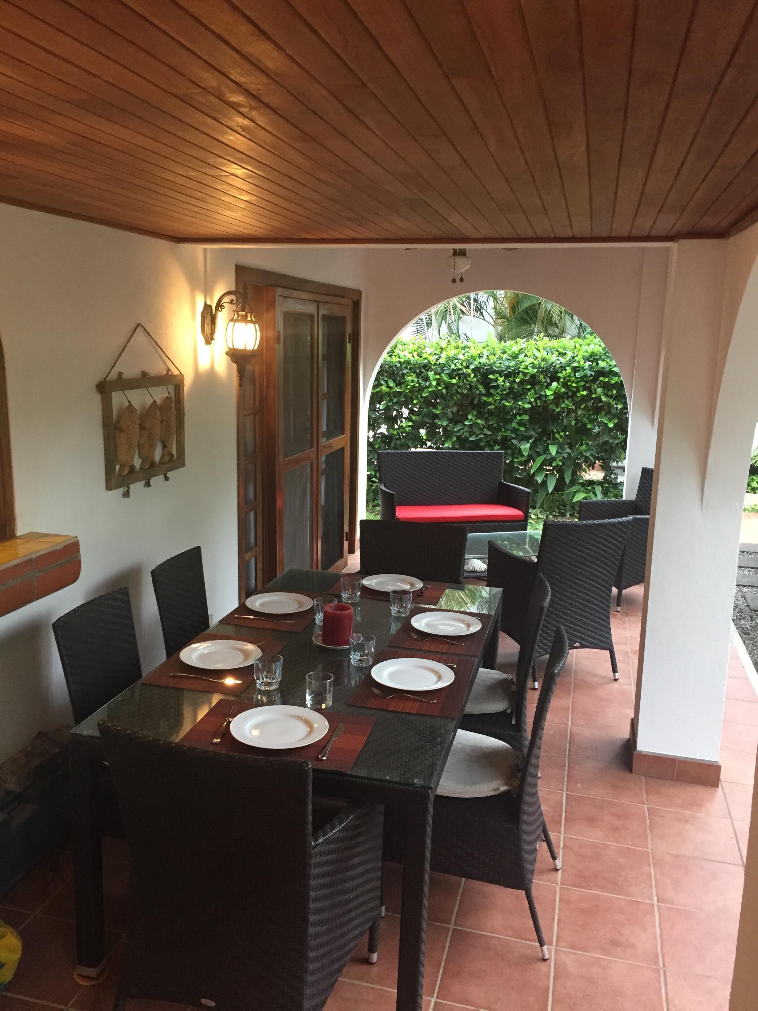 An outdoor dining area with a table set for six, surrounded by wicker chairs.