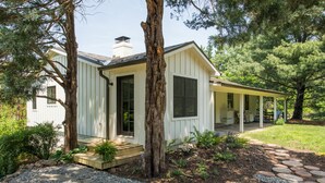 Ein eingeschossiges Haus mit Veranda, umgeben von Bäumen und einem Garten.