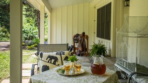Eine Veranda mit Tisch, der für Getränke gedeckt ist, einer Karaffe und einem Vogelkäfig.
