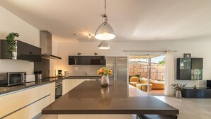 A modern kitchen with a central island, stainless steel appliances, and a hanging pendant light. - Luxury Villa del Duque in Chayofa, dream location, private pool, sea views, golf (Chayofa)