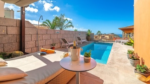 A poolside area with a lounge chair, a table with a bottle of champagne, and potted plants. - Luxury Villa del Duque in Chayofa, dream location, private pool, sea views, golf (Chayofa)
