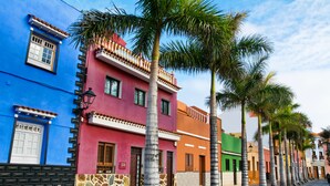 A row of colorful buildings with palm trees lining the street. - Luxury Villa del Duque in Chayofa, dream location, private pool, sea views, golf (Chayofa)