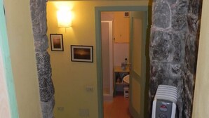 Un arco de piedra que da acceso a un baño con lavabo y secamanos.