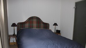 A bedroom with a bed, two nightstands, a lamp on each, and a plaid headboard.