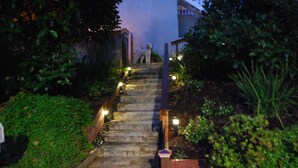 A stone staircase with a dog statue at the top, surrounded by greenery and illuminated by small lights. - Hidden Villa- A Hidden Paradise with beautiful furnished garden patio (San Diego)