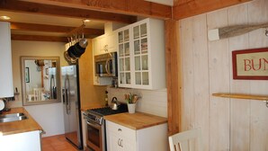 A kitchen with white cabinets, stainless steel appliances, and wooden beams. - Hidden Villa- A Hidden Paradise with beautiful furnished garden patio (San Diego)