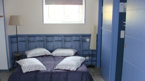 Una habitación con cama, ventana, lámpara y puerta.