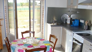 Una cocina con mesa, sillas, cafetera y pileta.
