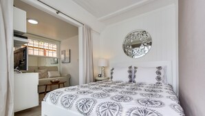 A bedroom with a bed, a bedside table, a mirror, and a view of the living area. - Sandcastle Hideaway, Dog Friendly, Designer Studio, Private Patio And Parking! (La Jolla)