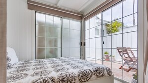 A bedroom with a bed, a sliding glass door leading to a patio with outdoor furniture and plants. - Sandcastle Hideaway, Dog Friendly, Designer Studio, Private Patio And Parking! (La Jolla)