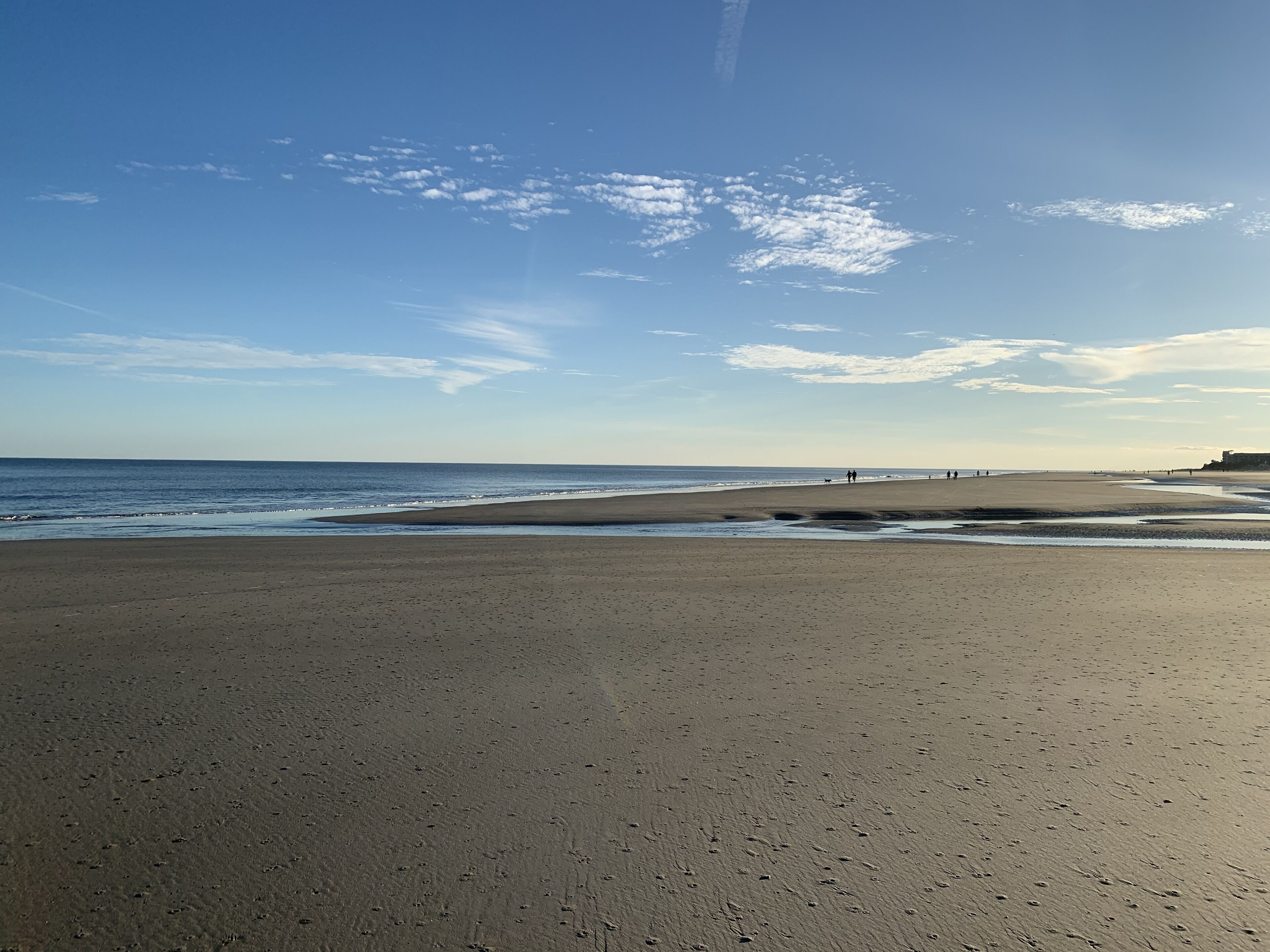 A wide sandy beach with gentle waves and a clear sky.