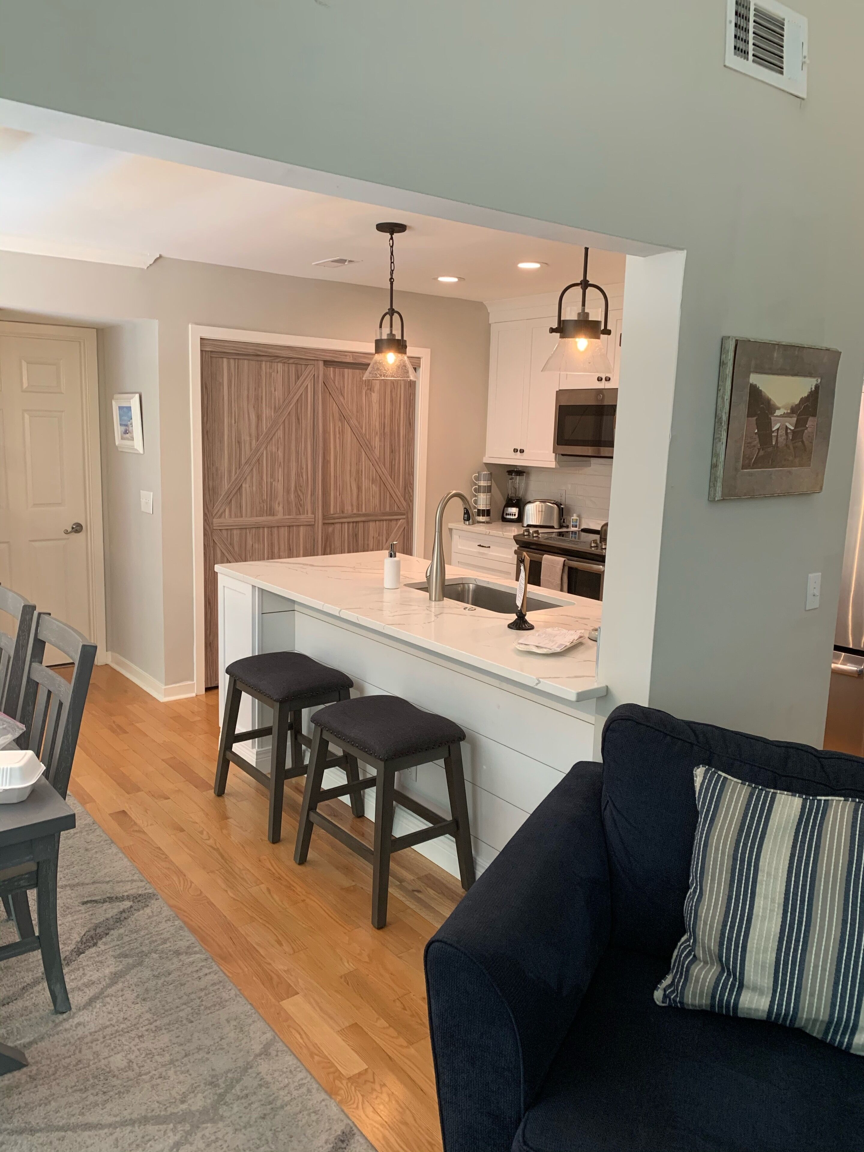 A modern kitchen with a central island, bar stools, and pendant lighting.