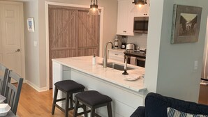 A modern kitchen with a central island, bar stools, and pendant lighting. - Palmetto Dunes-Golf-Pickleball-Tennis- Beach! (Hilton Head Island)