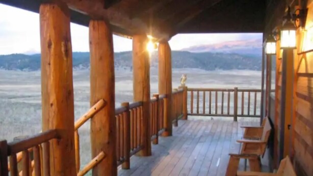 Una terraza de madera con bancos, barandilla y vistas a un paisaje nevado.