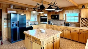 Una cocina amplia con armarios de madera, una isla central y electrodomésticos modernos.