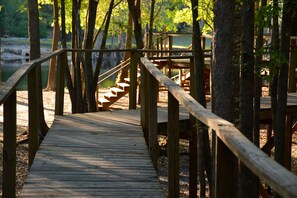 Un paseo marítimo de madera que lleva a una escalera de madera, rodeado de árboles.