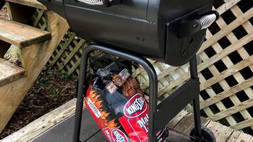 A black RiverGrille barbecue grill with a Kingsford charcoal bag underneath.