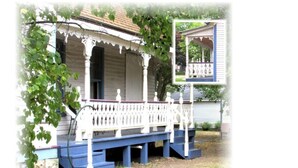 A porch with a white railing and blue steps, surrounded by greenery.