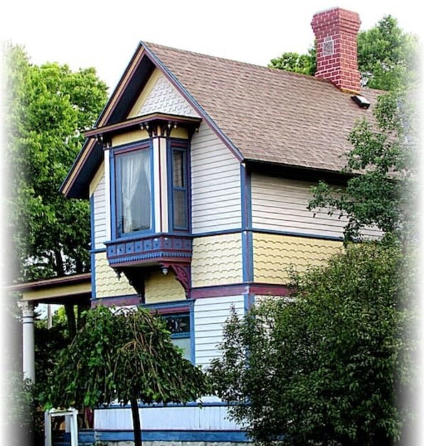 A two-story house with a bay window and a red brick chimney.