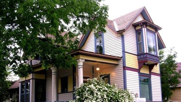 A two-story house with a porch, large windows, and a well-maintained lawn.