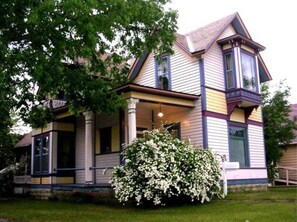 A two-story house with a porch, large windows, and a well-maintained lawn.