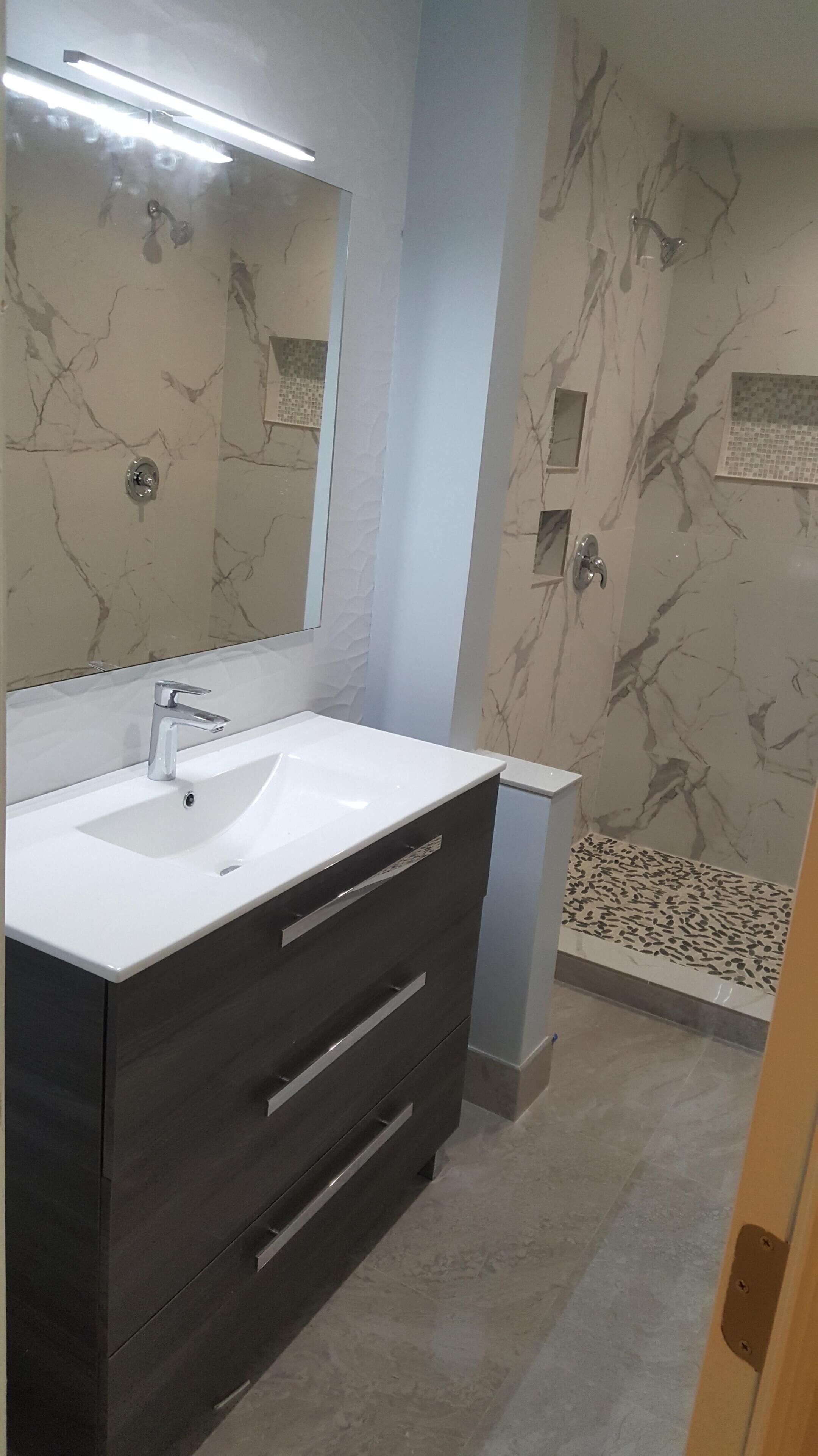 A bathroom with a white sink, dark wooden vanity, and a mirror.