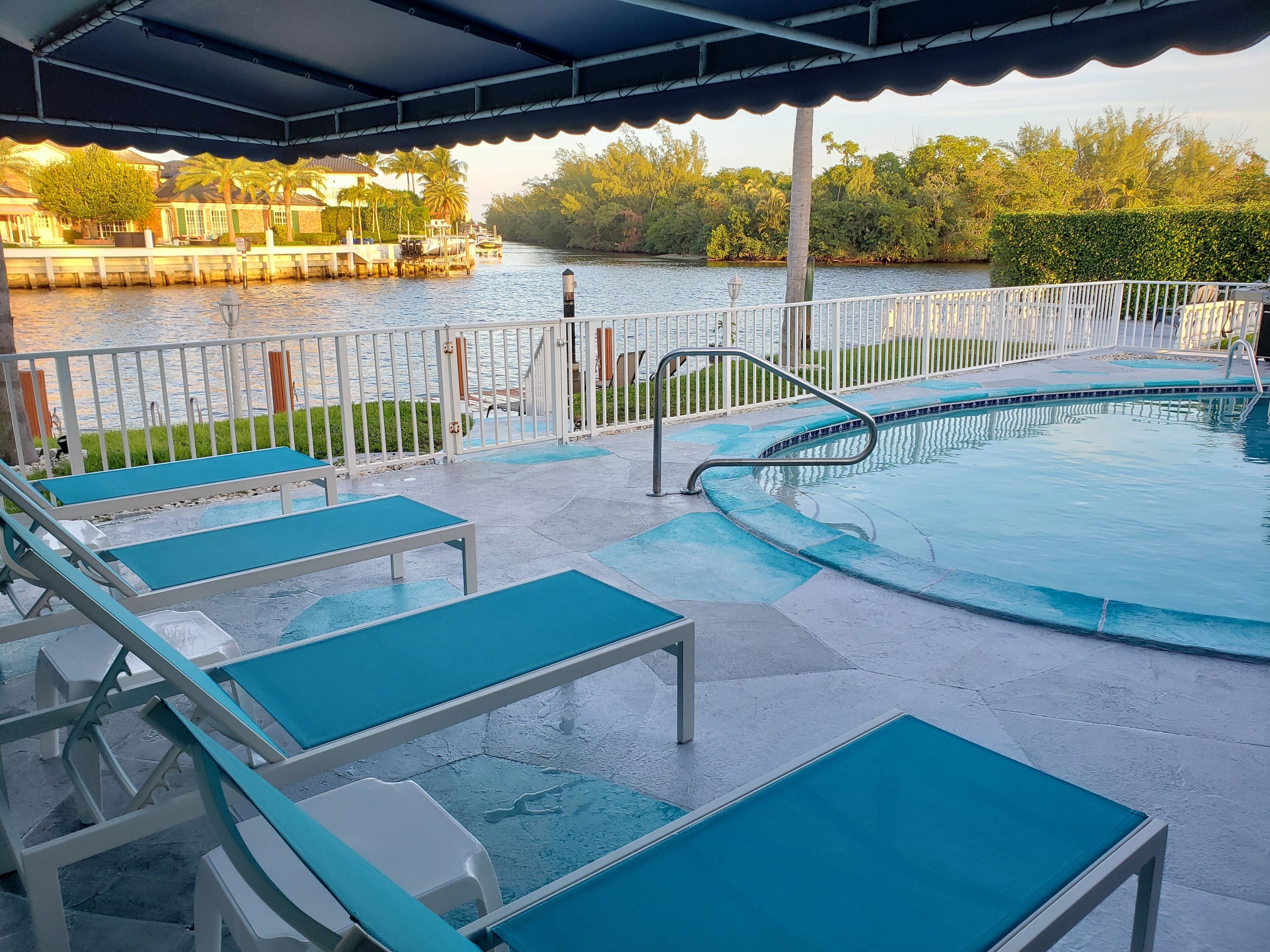 A swimming pool with lounge chairs and a view of a river.