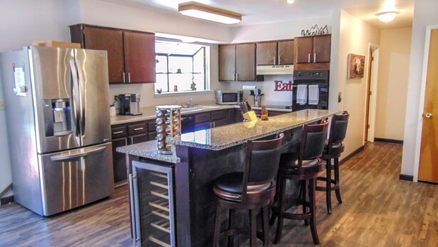 Una cocina moderna con electrodomésticos de acero inoxidable, una isla central con taburetes altos y suelo de madera.