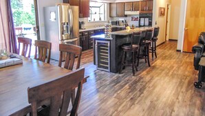 Cocina moderna con una isla central, mesa de comedor de madera y taburetes de bar.