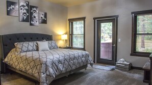 A bedroom with a large bed, a nightstand, a lamp, and a door with a view. - Beautiful Getaway! All paved roads, garage, Snowmobile, Terry Peak, Deadwood (Lead)